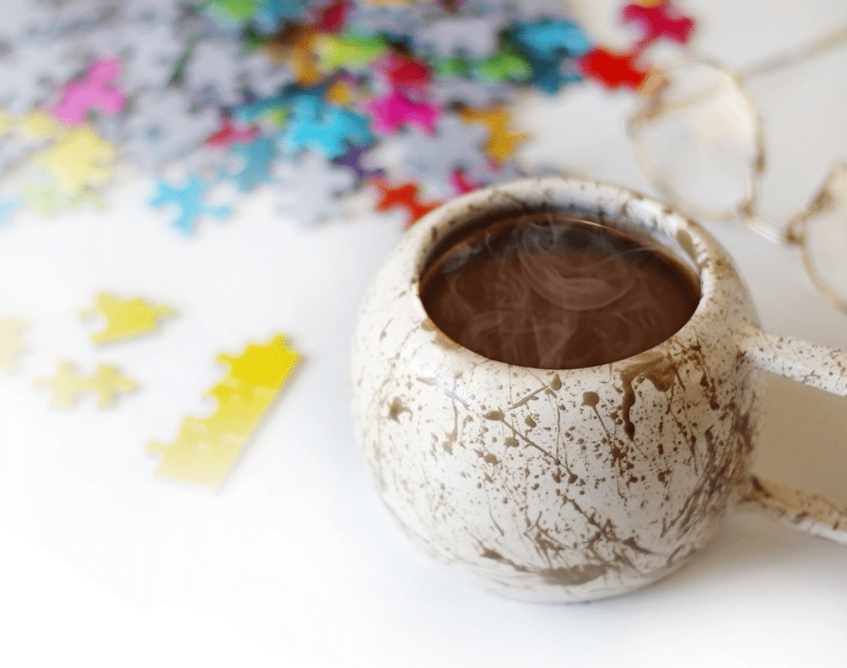 A cuppa coffee on the table with a puzzle on the background