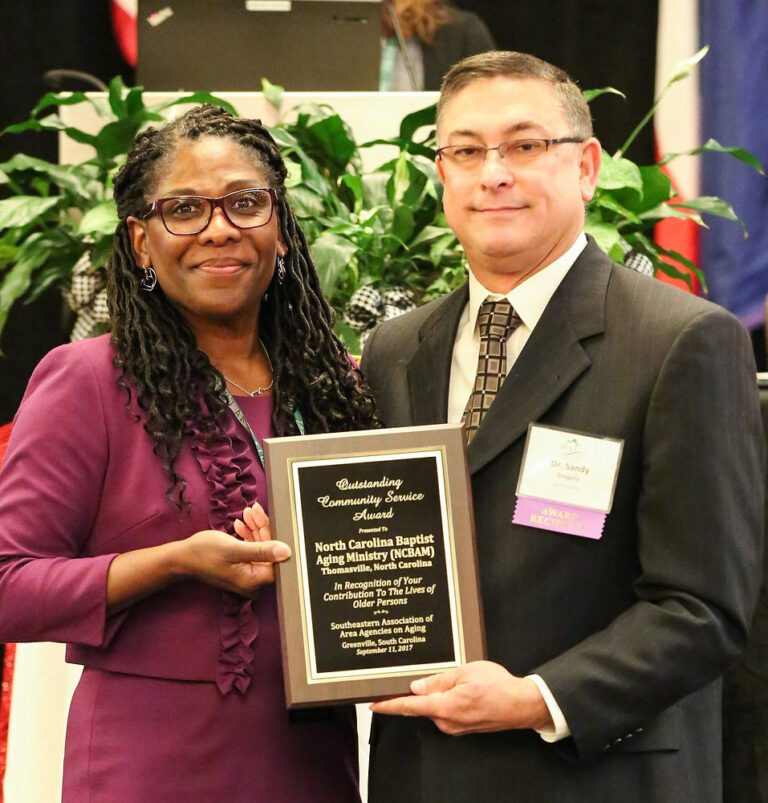 Two people hold an Outstanding Community Service Award plaque presented to North Carolina Baptist Aging Ministry.