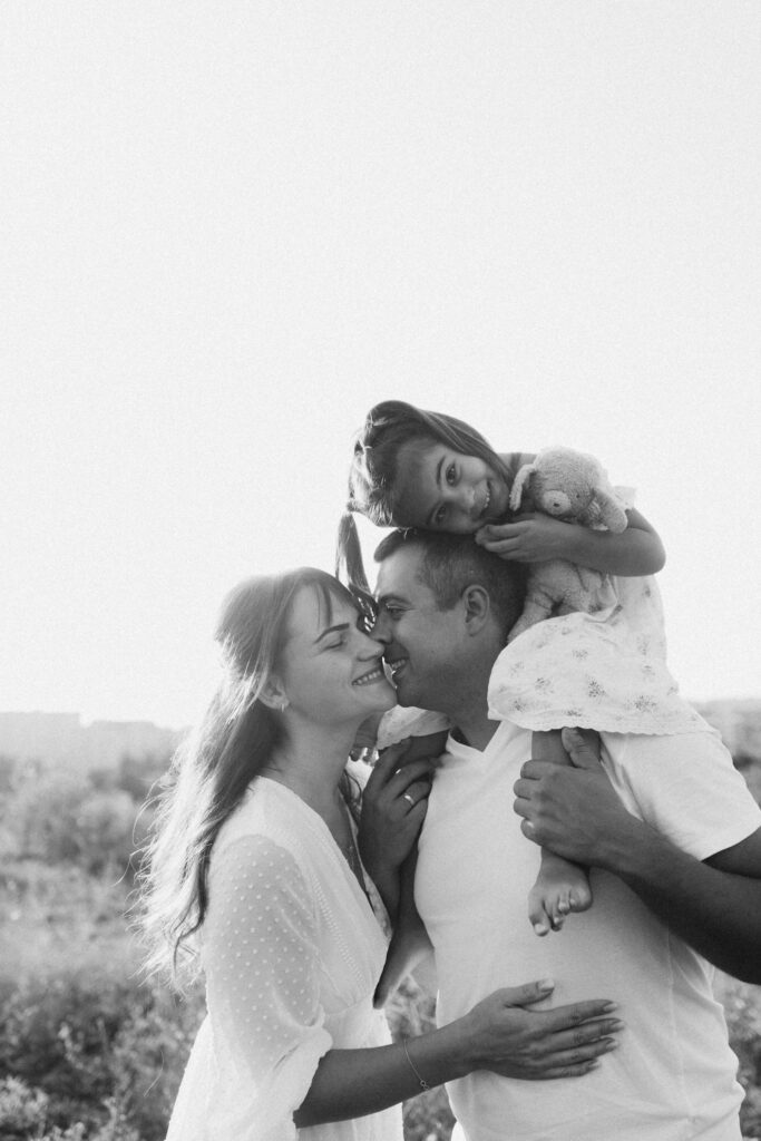 Heartwarming black and white family portrait outdoors with parents and child.