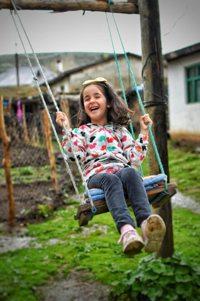 A happy child enjoying a sunny day on a swing in a rural setting, showcasing innocence and joy.