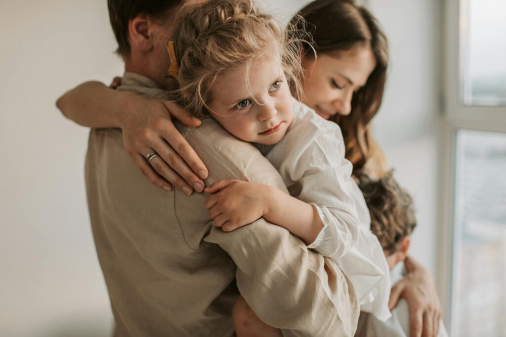 A young family shares a tender embrace inside a cozy home setting, highlighting love and togetherness.