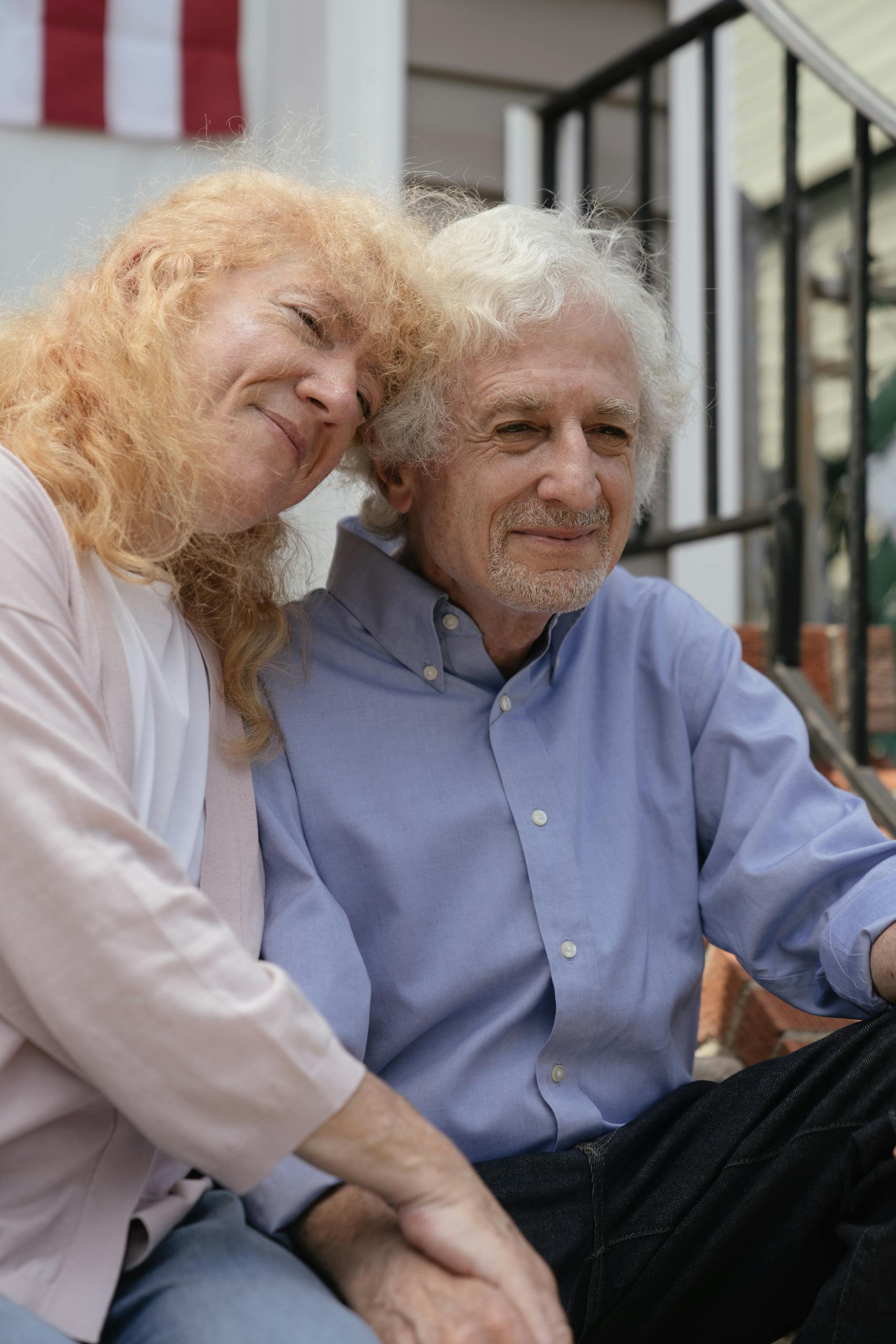 An affectionate elderly couple embracing while seated outdoors, capturing their closeness and happiness.
