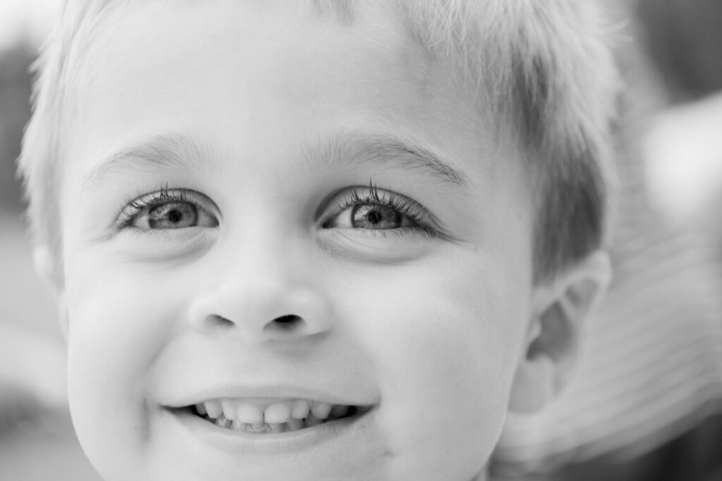 Close-up black and white portrait of a smiling child, capturing innocence and joy.