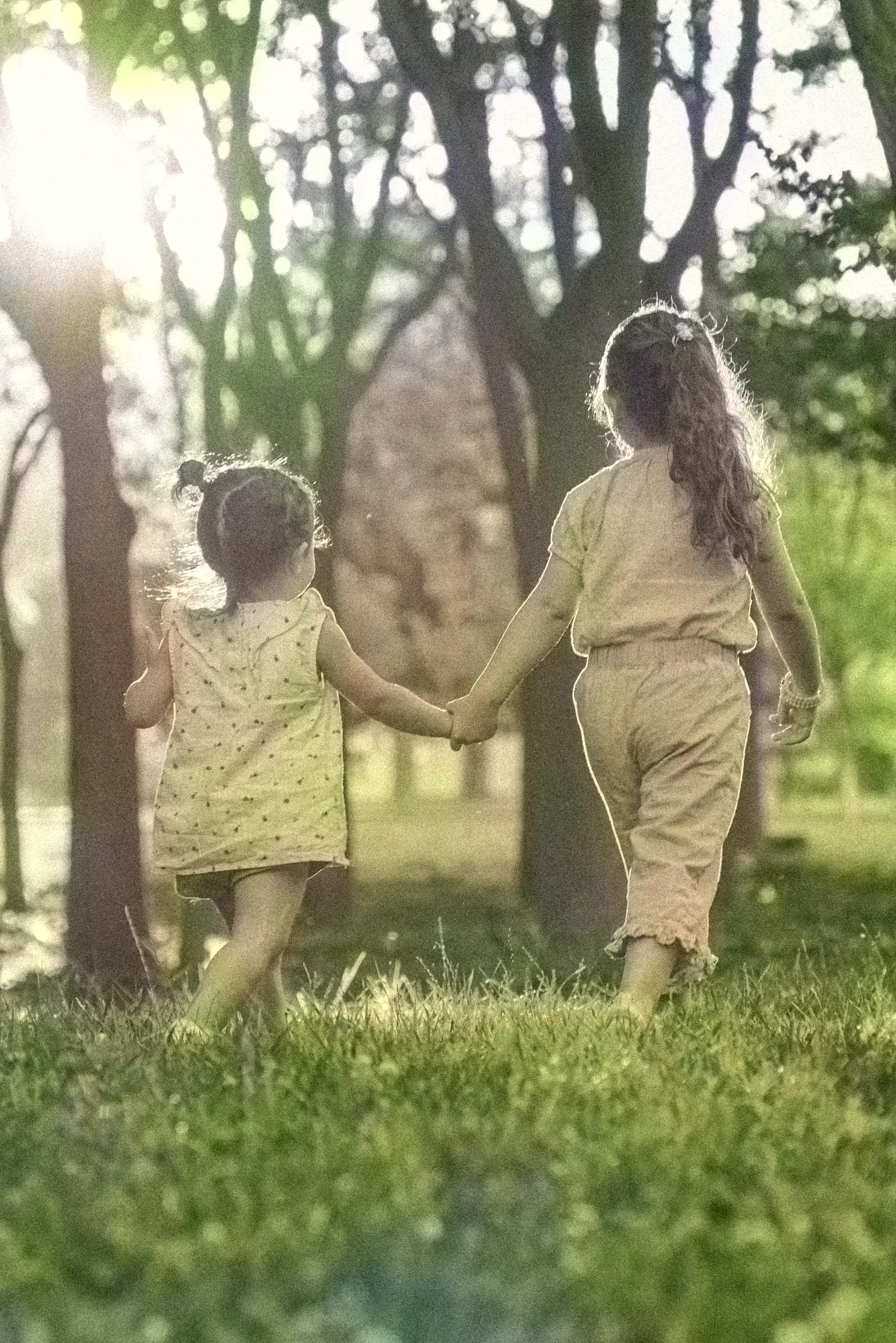 Two children walking hand in hand in a sunlit park, creating a warm family moment.