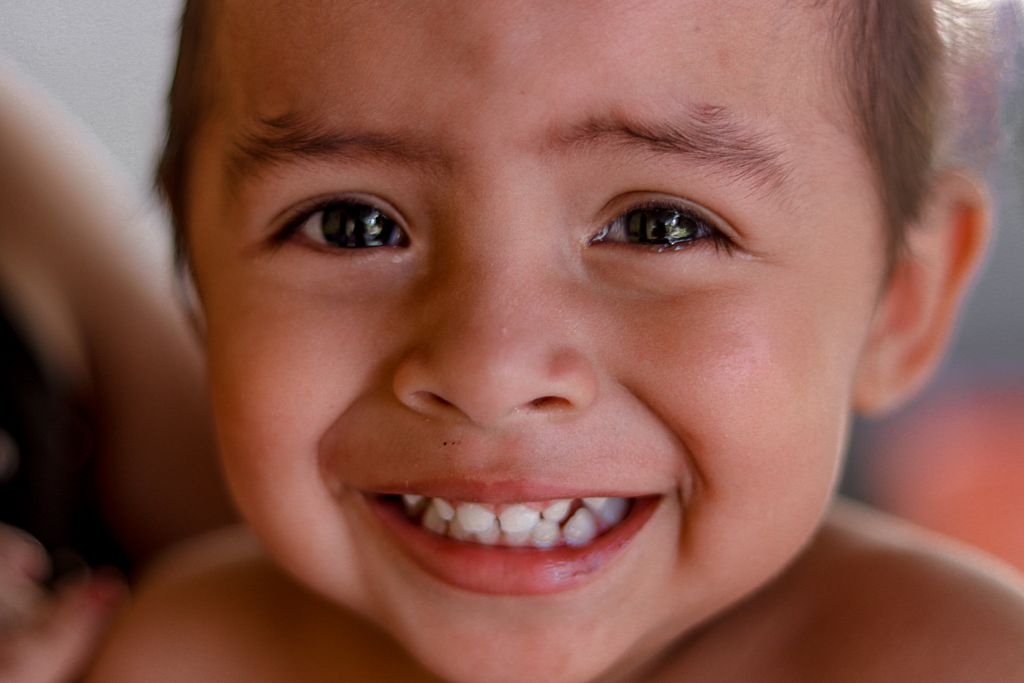 Close-up portrait of a smiling young child with bright eyes and a joyful expression.