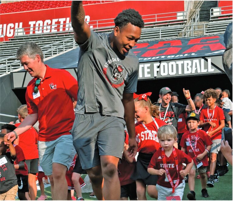 NC State Wolfpack football players lead Baptist Children’s Homes foster and adoptive families and children onto the field at Carter-Finley Stadium