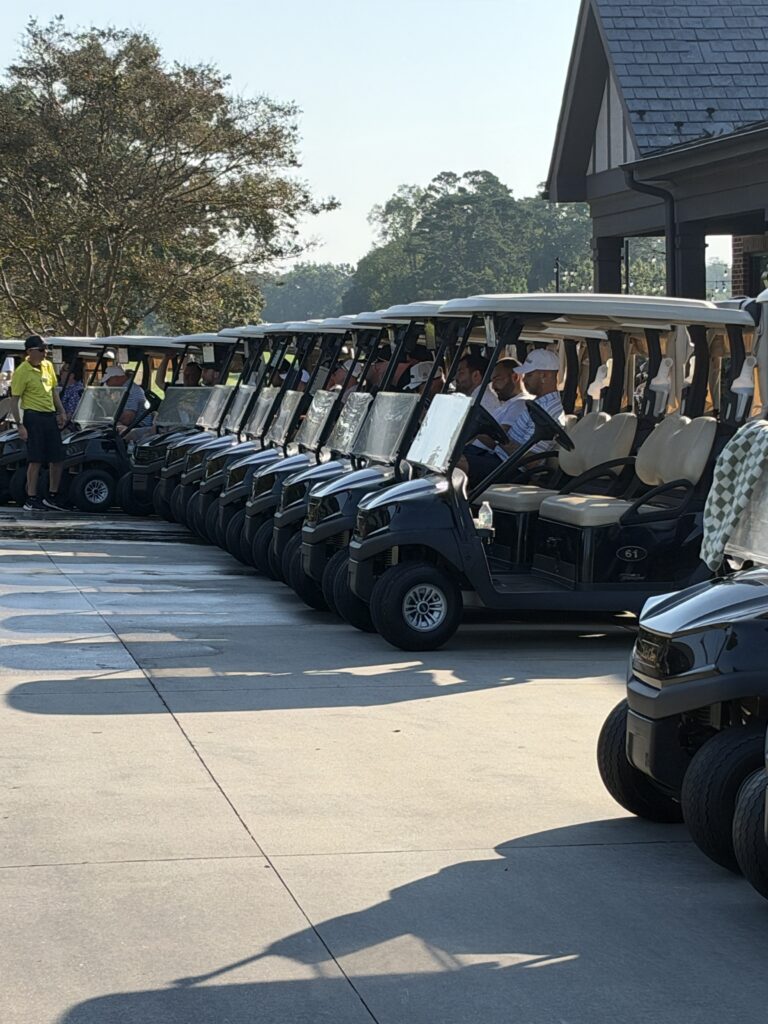 Golf carts lined up in rows with players seated, ready to start the BCH Golf Classic at Sedgefield Country Club.