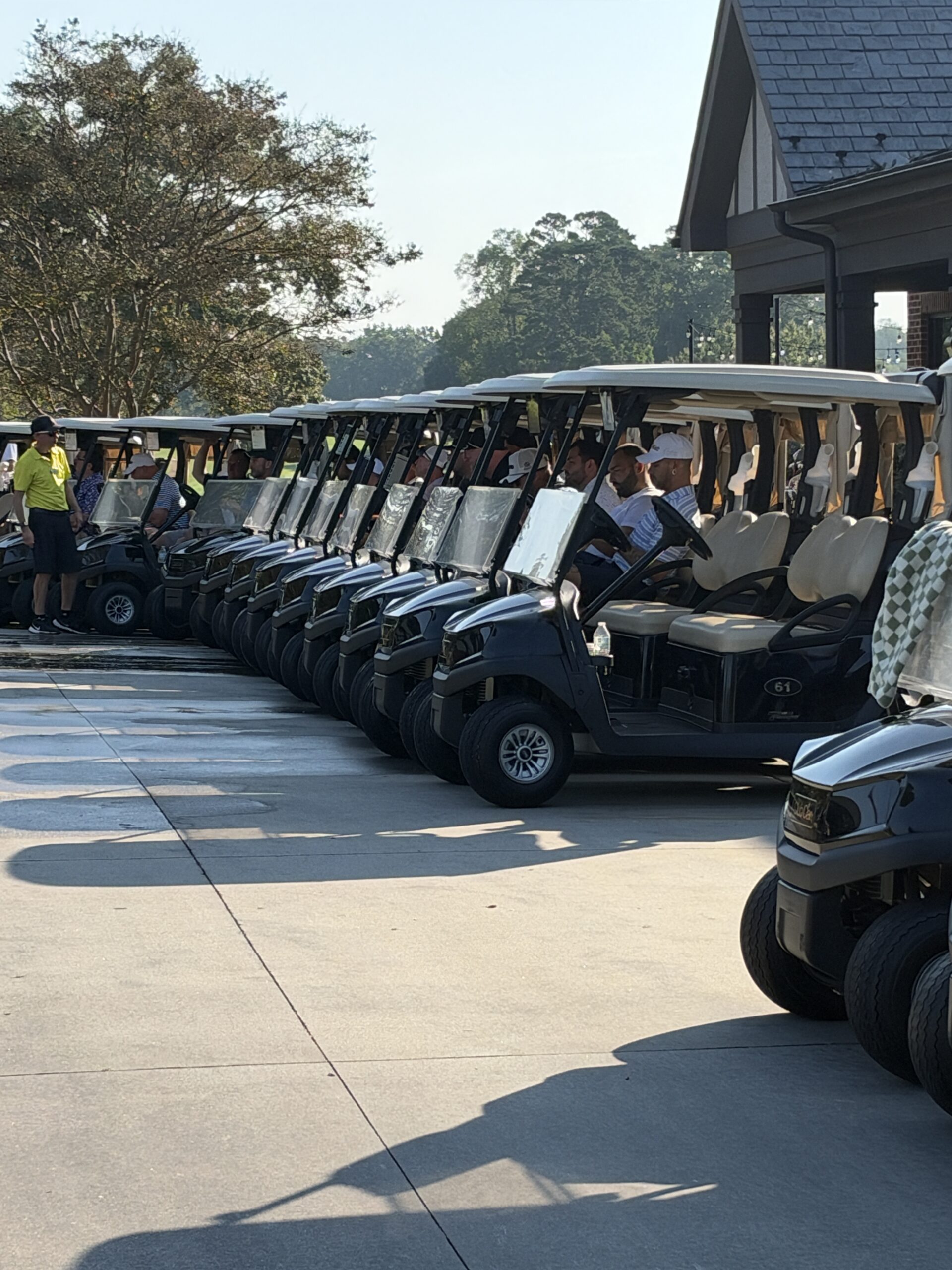 Golf carts lined up in rows with players seated, ready to start the BCH Golf Classic at Sedgefield Country Club.