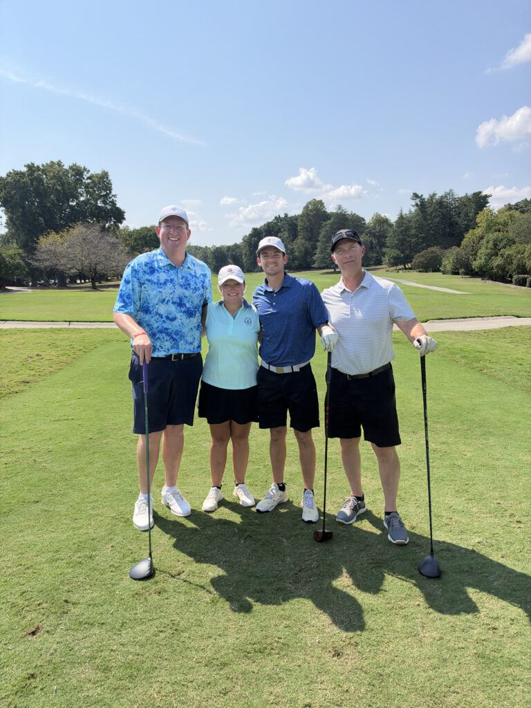 Four golfers pose with clubs on a sunny fairway at the BCH Golf Classic at Sedgefield Country Club.