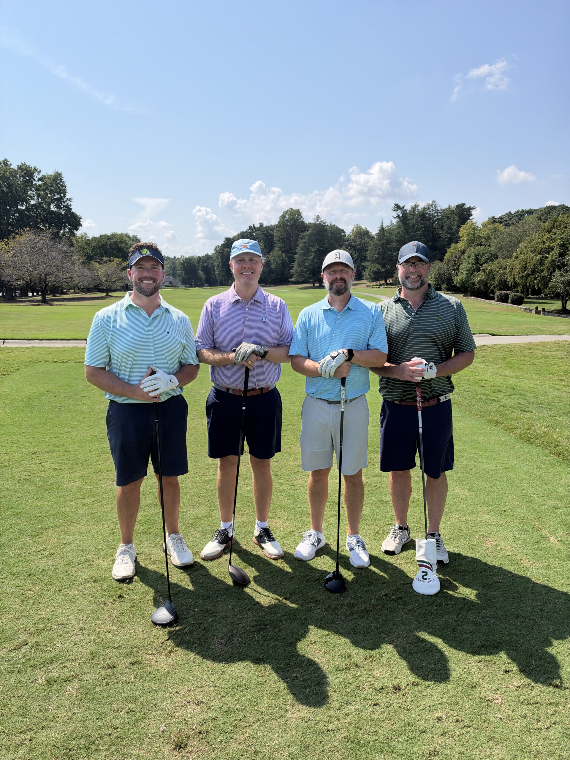 Four golfers pose with clubs on a sunny fairway at the BCH Golf Classic at Sedgefield Country Club.