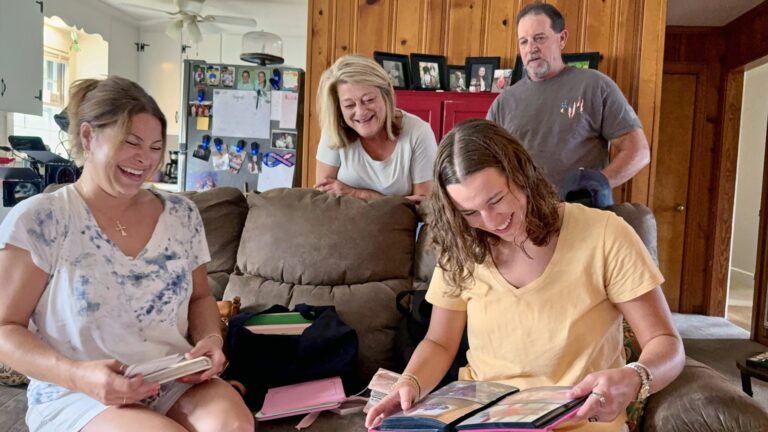 Olivia, Noelle, Robin, and Sam look through family photographs together.