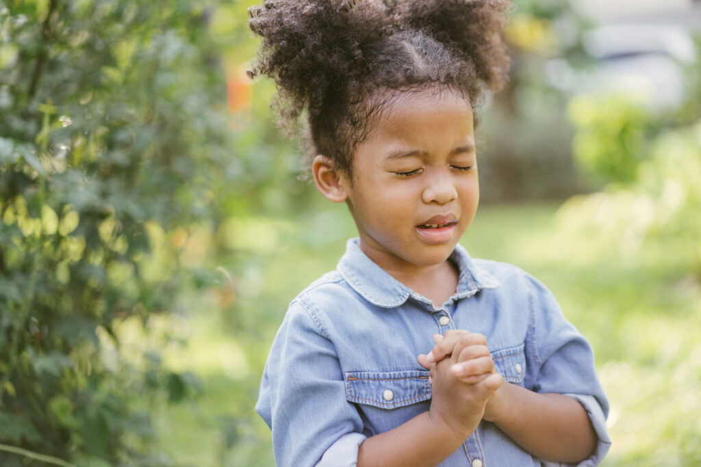 A young girl with her hands folded in prayer