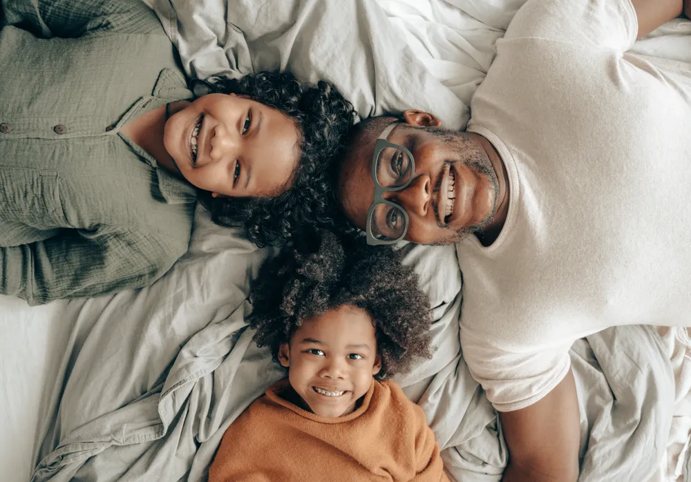 Smiling mother, father and young daughter lying together and laughing