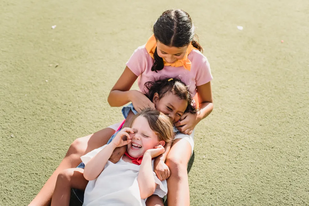 Three smiling children laughing and playing together outdoors
